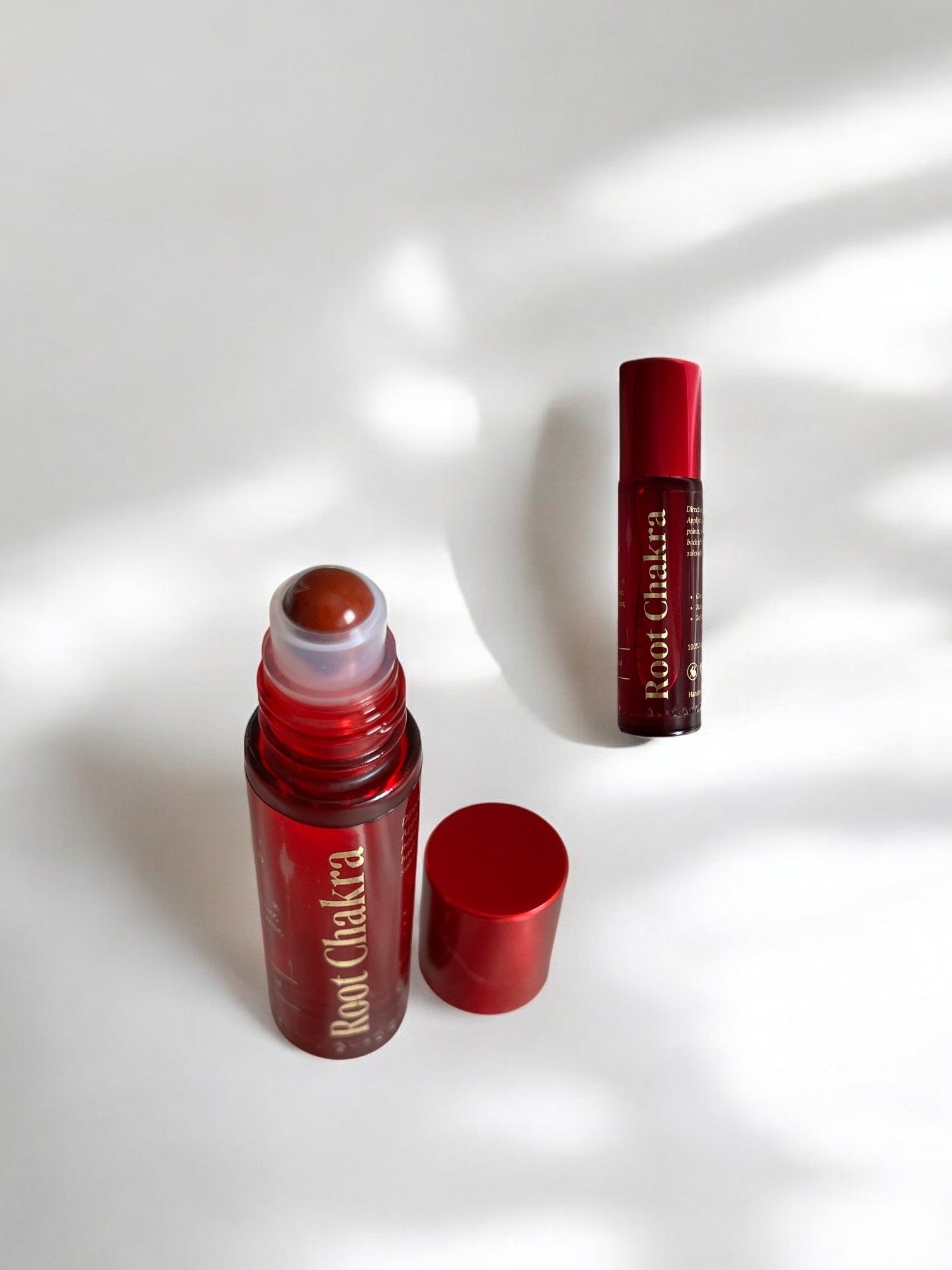 Sheba Scents Root Chakra Essential Oil Roll-On with red glass bottle and red jasper roller ball, infused with vetiver, myrrh, frankincense, grapefruit, and pine for grounding and stability.