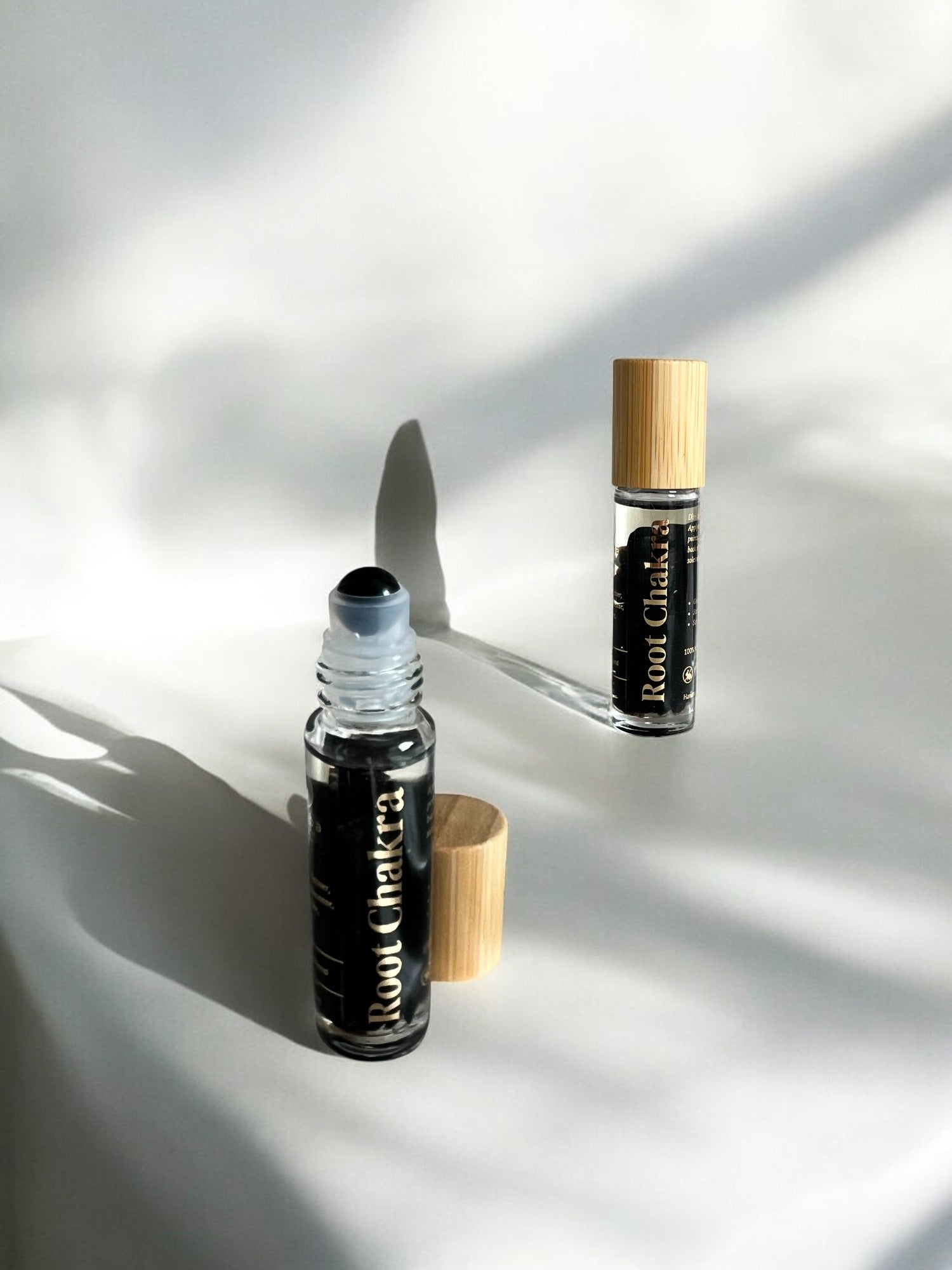 Sheba Scents Root Chakra Roll-On featuring black obsidian crystal filled bottle designed to support grounding, emotional stability, and root chakra healing.