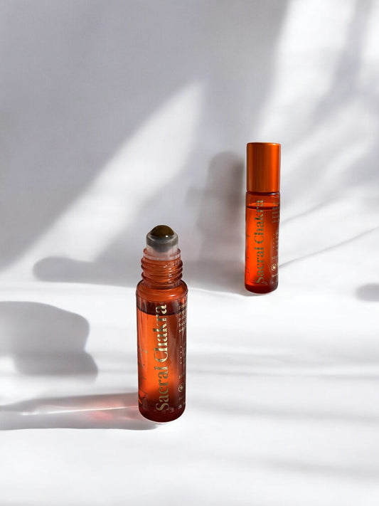 Sheba Scents Sacral Chakra Essential Oil Roll-On with orange glass bottle and crystal roller ball, infused with sandalwood, jasmine, cardamom, cinnamon, patchouli, and tangerine for creativity and emotional healing.