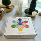 Set of seven Sheba Scents chakra candles in frosted glass jars, each one is reiki-infused, chakra specific colored jars, and made with an original aromatherapy blend